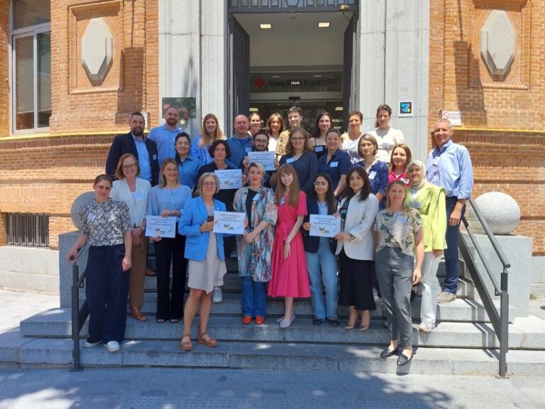 A group of people pose for the photo in front of the Spanish Red Cross building